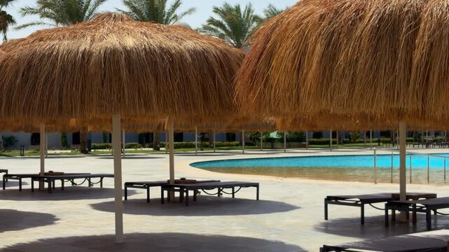 Serene Daytime Retreat Featuring Strawcovered Umbrella Over Shimmering Blue Water And Tiled Flooring