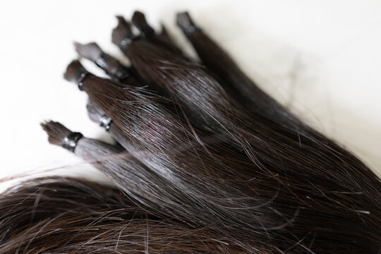 Bundles of dark human hair extensions or donation on white background