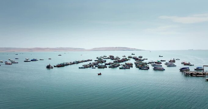 Large fleet of traditional fishing boats gathered in bay of Paracas, an important hub for fishing industry in Peru. Aerial drone, copy space