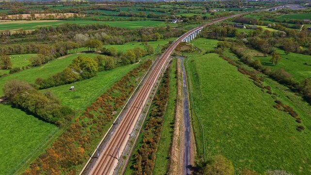 Railway corridor on Paris Montparnasse to Brest line in Mayenne department Pays de la Loire region France crossing bocage farmland with pasture and hedgerow fields, drone forward tracking shot