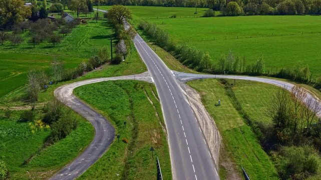 Dual carriageway junction with slip road connection in Mayenne department Pays de la Loire region France within bocage farmland landscape, drone forward glide aerial shot