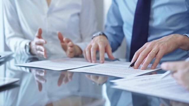 Diverse business people discussing contract papers before signing. Teamwork of lawyers are at work at the glass desk in office