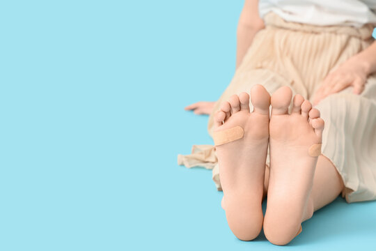 Legs of young woman with callus patches on blue background