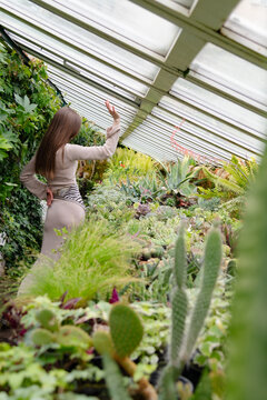 Woman in greenhouse surrounded by various plants and cacti during daytime in a tropical setting
