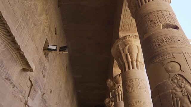 Ancient Egyptian Philae Temple. with massive carved stone columns covered in hieroglyphs, low angle view highlighting detailed reliefs and architectural grandeur.