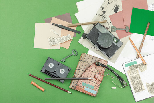 Flat lay with vintage camera, cassette, notebook, key and research tools on green background