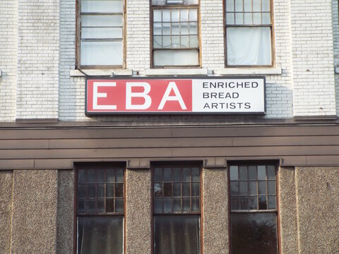 Ottawa, Ontario, Canada &ndash; August 03, 2025: A signage for Enriched Bread Artists (EBA) is mounted on the brick exterior wall of an older, multi-story industrial building at 951 Gladstone Ave.