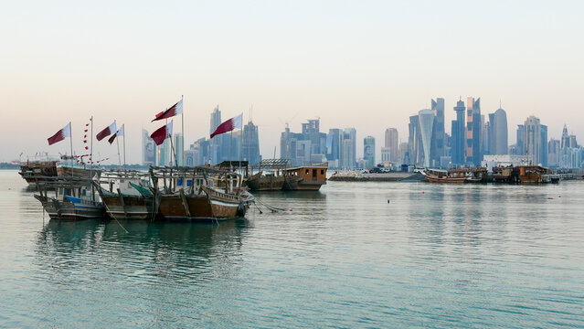 Traditional dhow boats with Qatar flags and Doha skyline on the Corniche, Arabian Gulf