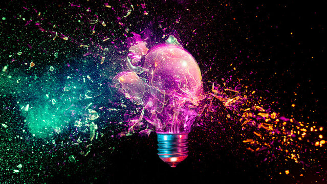 Lightbulb exploding into colorful particles black background