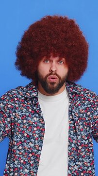 Shocked amazed surprised man with Afro hairstyle wig touching his head showing hands brain explosion wow gesture, professional burnout, celebrating success victory win. Guy isolated on blue background