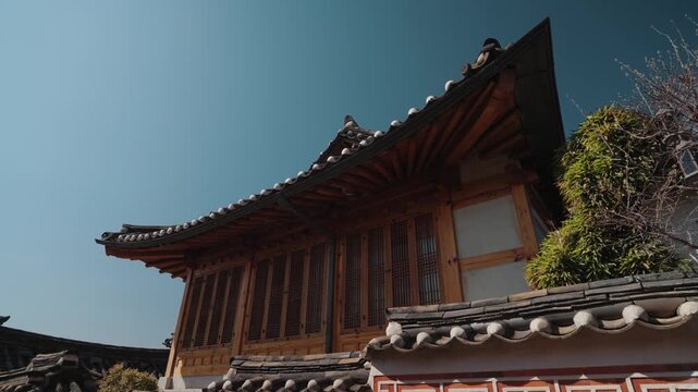 Traditional Korean hanok house architecture in Bukchon Hanok Village, Seoul, South Korea, featuring wooden details, curved tiled roof, and historic residential design under clear blue sky.