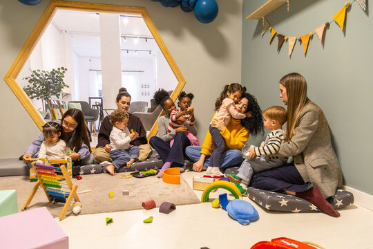 Diverse parents playing with young children in nursery