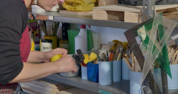 Artisan Workshop: A focused craftsperson meticulously organizes tools and materials within a well-lit workshop, illustrating the dedication and artistry of their trade.