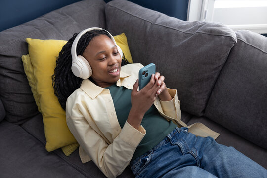 Teen Girl Relaxing with Headphones and Phone on Couch