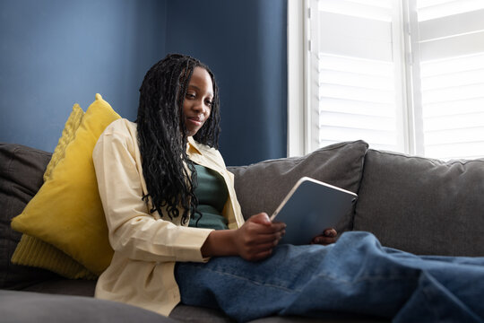 Teenage girl using a digital tablet at home on the sofa