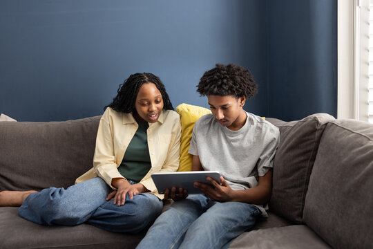 Two Teens Enjoying Tablet Together sitting on the couch