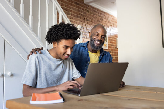 Father supporting son during laptop study session