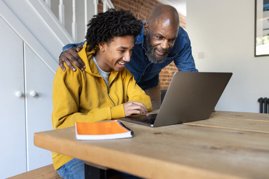 Son showing father his school grades on a laptop