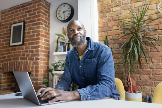 Thoughtful Man Working on Laptop at home in his kitchen