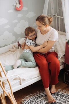 Mother cuddling child with physical disability at home