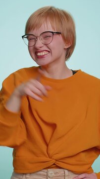 Amused short haired woman pointing finger to camera, laughing out loud, taunting making fun of ridiculous appearance, funny joke anecdote. Pretty blonde lady isolated alone on blue studio background