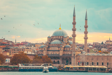 Obraz premium Sunset in Istanbul. New Valide Sultan Mosque on the shore of the Golden Horn. Seagulls flying.