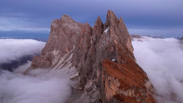 Flying above Odle ridge near Seceda in Dolomites, Italy. Fog float in the valley underneath the mountain