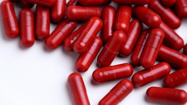Top view of bright red vitamin C capsules on a white background. Pharmaceutical supplement pills. Concept of healthcare and medical treatment. Rotation