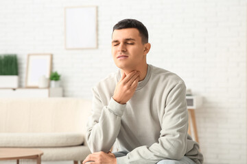 Fototapeta premium Young man with thyroid gland problem at home