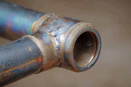 Close up showing raw brazed joints on a steel bicycle frame bottom bracket, highlighting metalworking craftsmanship and texture