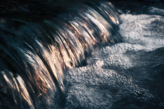 Nature's beauty: closeup of small water cascade on a natural stream reflecting the pleasant sunlight