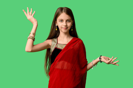 Cute little Indian girl in sari dancing on green background. Divaly celebration