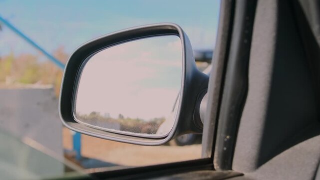 Driver adjusting side mirror in car for better visibility and safety, close-up view of vehicle interior, driving preparation and road awareness concept, transportation and control while traveling