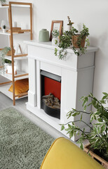 Naklejka premium Interior of living room with electric fireplace, shelf unit and houseplants