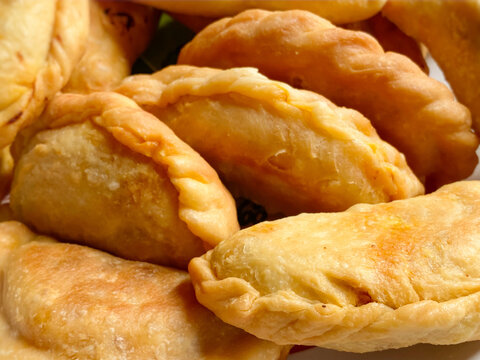 Close up detail of crispy Malaysian karipap curry puff showing golden fried pastry texture.