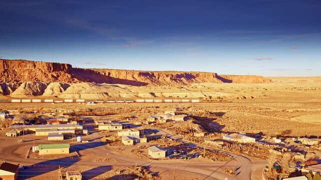 High-angle drone shot of a long freight train passing through scenic western land