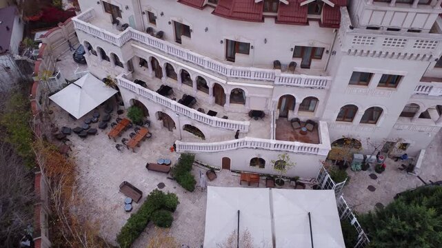 Aerial drone view of Suter Palace in Bucharest, a grand early 20th-century white mansion with terracotta roofs, arched arcades, and terraces near Carol Park.