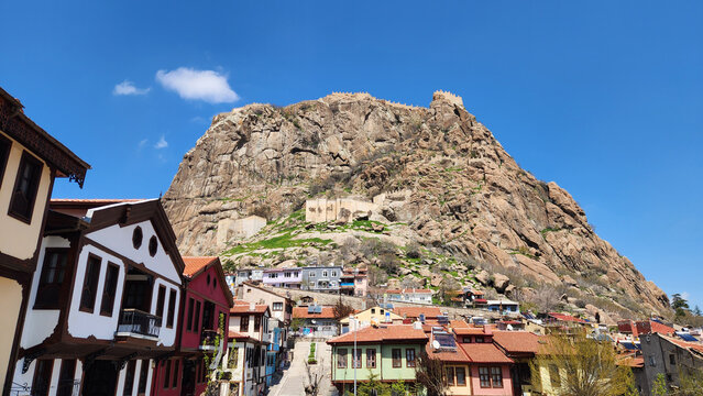 Afyonkarahisar Castle rises dramatically above the city, a volcanic rock fortress with ancient origins. Below it, the old town features traditional Ottoman houses and narrow streets, reflecting centur