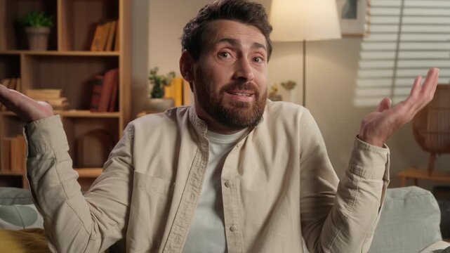 Confused unsure doubtful Caucasian middle-aged man shrugging shoulders looking at camera at home living room couch adult male feeling hesitate doubt question shrug uncertain reaction shaking head no