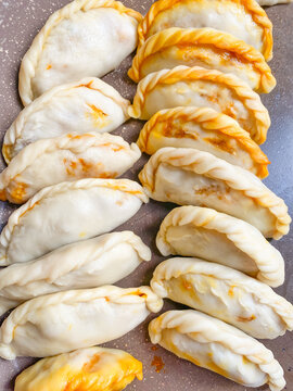 Uncooked Malaysian karipap curry puff arranged before frying, showing handmade pastry with potato and chicken filling.