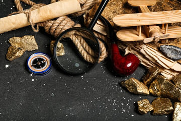 Travel equipment with smoking pipe, old manuscripts and golden nuggets on grunge black background © Pixel-Shot