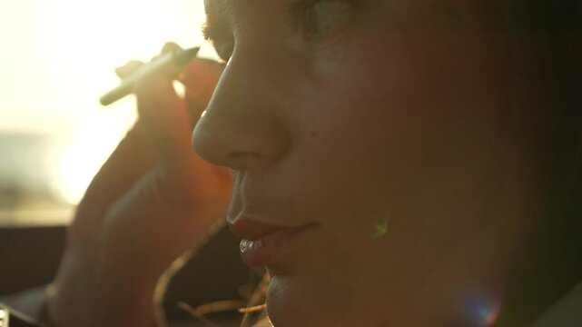 Makeup application car young woman applies eyebrow pencil inside vehicle by the ocean during a golden hour sunset