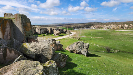 Naklejka premium Göynüş Castle (Köhnüş Castle) is a Phrygian rock complex opposite Aslantaş in Göynüş Valley, featuring carved rooms, tunnels, and cisterns used for settlement and defense, surrounded by a large necrop