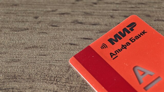 Sosnoviy Bor, Russia - April 21, 2026: MIP payment card from Alfa Bank displayed on a wooden surface, showcasing the card design and branding elements clearly