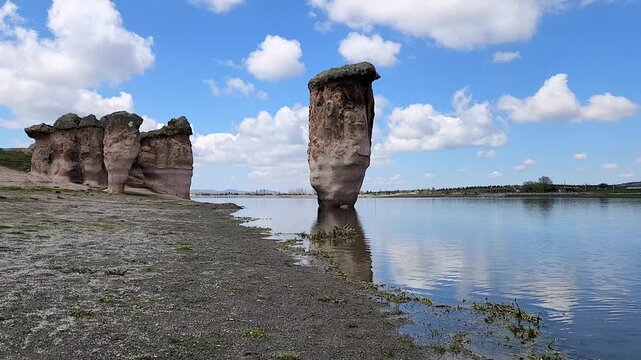 Emre Lake in spring, nestled under a vast blue sky with fluffy white clouds and surrounded by mysterious fairy chimneys