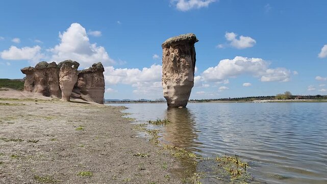 Emre Lake in spring, nestled under a vast blue sky with fluffy white clouds and surrounded by mysterious fairy chimneys