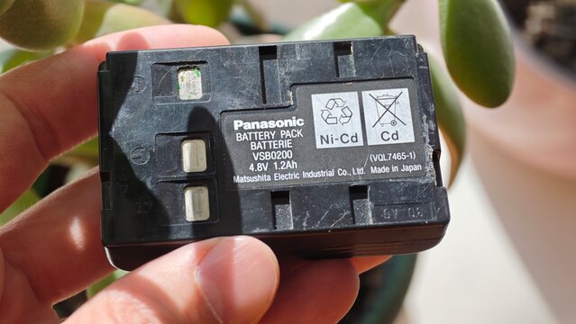 Sosnoviy Bor, Russia - April 28, 2026: Panasonic Ni-Cd battery pack VS82020 held in hand, showing label details and sunlight reflections on surface