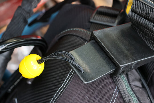 Detailed view of black parachute harness release handle with bright yellow emergency equipment component ready for safe extreme skydive action instilling confident secure emotion