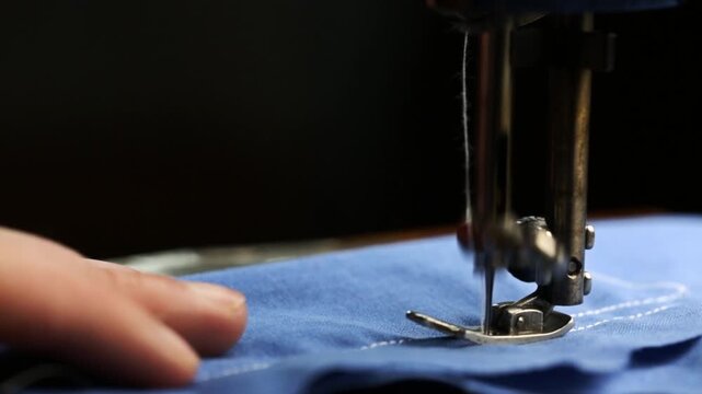 A seamstress works on a vintage sewing machine, sewing at home, a retro-style sewing machine in operation