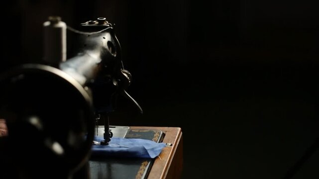 A seamstress works on a vintage sewing machine, space for text